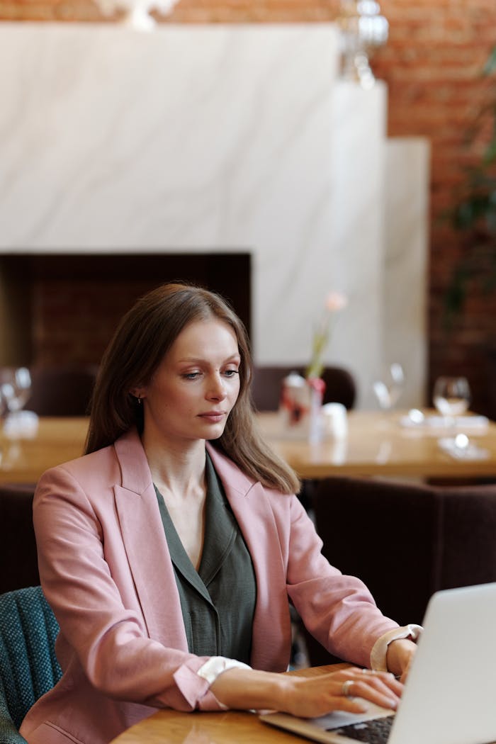 Professional woman in a cafe working on a laptop, showcasing modern telecommuting.